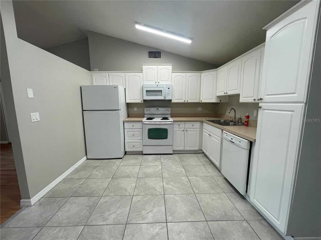 7986 Avenal Loop New Port Richey, FL 34655 - Photo 7 of 23 a kitchen with a stove a refrigerator and a sink