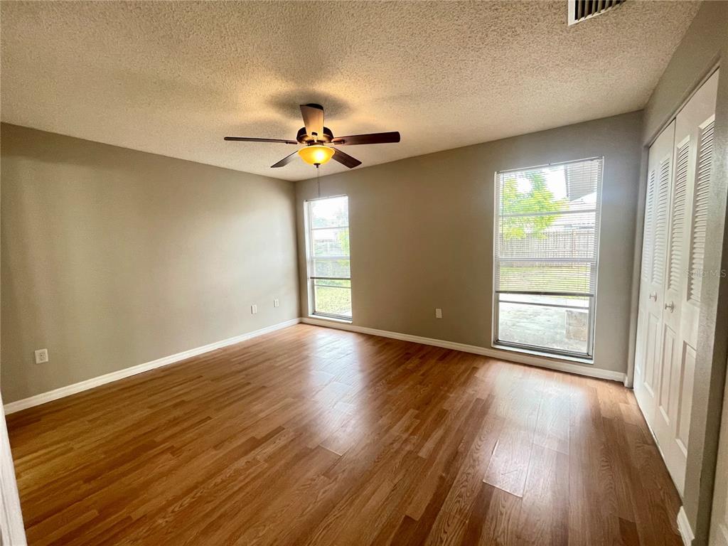 7986 Avenal Loop New Port Richey, FL 34655 - Photo 9 of 23 a view of an empty room with wooden floor and a window