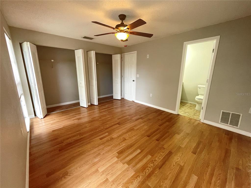 7986 Avenal Loop New Port Richey, FL 34655 - Photo 10 of 23 a view of an empty room with wooden floor and a ceiling fan