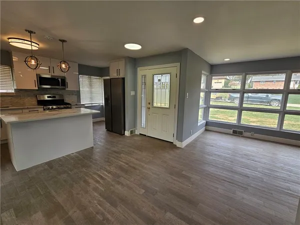 a kitchen with stainless steel appliances a refrigerator and wooden floor