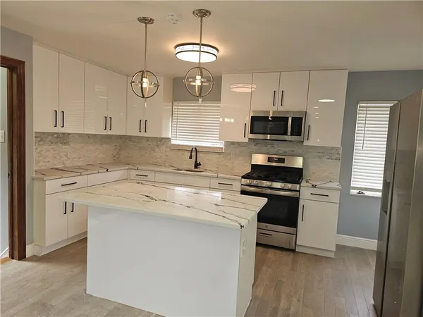 a kitchen with stainless steel appliances a stove a sink and white cabinets