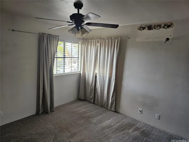 an empty room with windows and fan