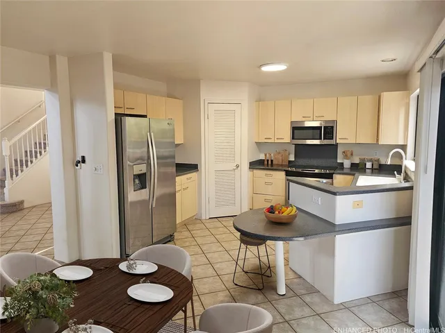 a kitchen with stainless steel appliances a refrigerator a stove a sink and a dining table
