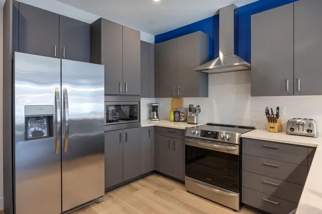 a kitchen with stainless steel appliances granite countertop a refrigerator a stove and a sink