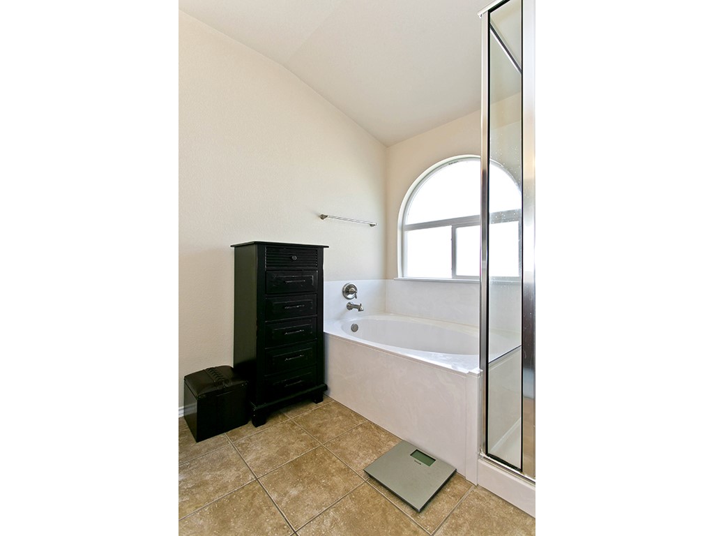 1808 Sand Creek Road Cedar Park, TX 78613 - Photo 17 of 25 Soaking tub with an arched window, complemented by a separate glass-enclosed shower