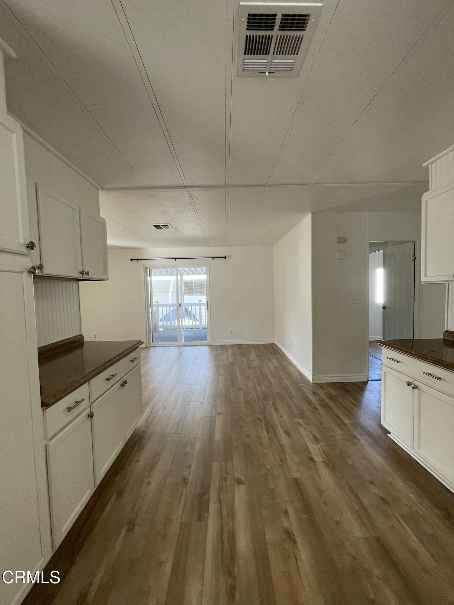 15750 Arroyo Drive, Unit 80 Moorpark, CA 93021 - Photo 15 of 19 a kitchen with granite countertop a stove a sink and white cabinets with wooden floor