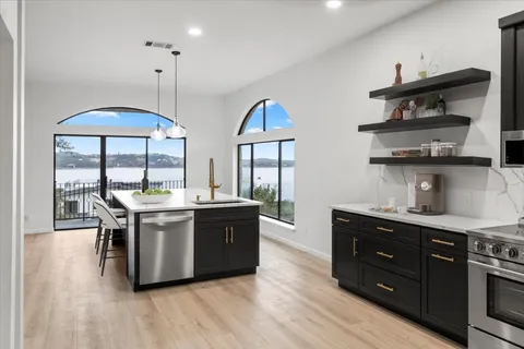 a kitchen with stainless steel appliances granite countertop a stove and a wooden floor