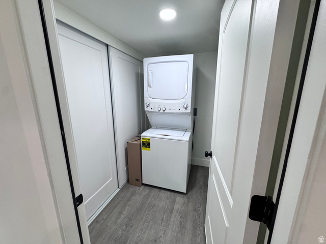 4729 Middleboro Road Herriman, UT 84096 - Photo 5 of 19 Dedicated laundry space featuring a stacked washer and dryer unit, wood-finish flooring, and bright overhead lighting