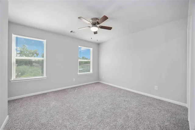 an empty room with windows and fan