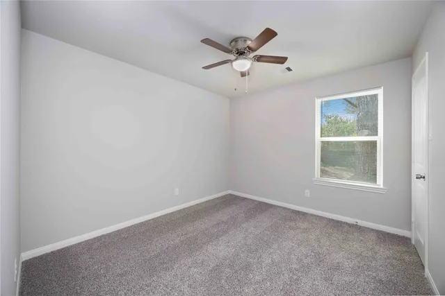 an empty room with a window and a fan