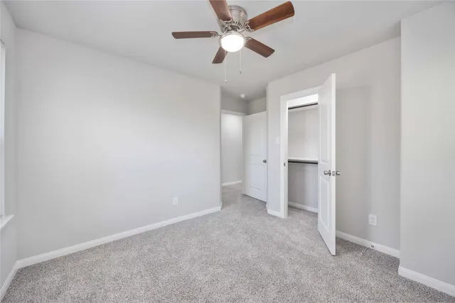 an empty room with closet and a ceiling fan