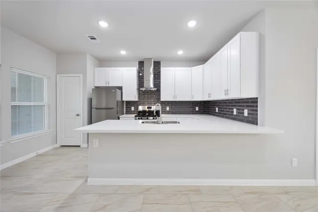 a view of kitchen with stainless steel appliances granite countertop a refrigerator a stove a sink and white cabinets with wooden floor