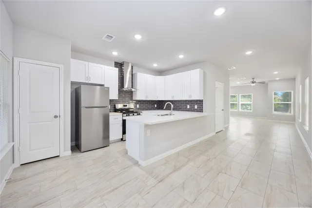 a large white kitchen with a refrigerator a kitchen island a sink and a stove