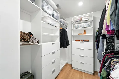 a view of walk in closet with clothes and shoes