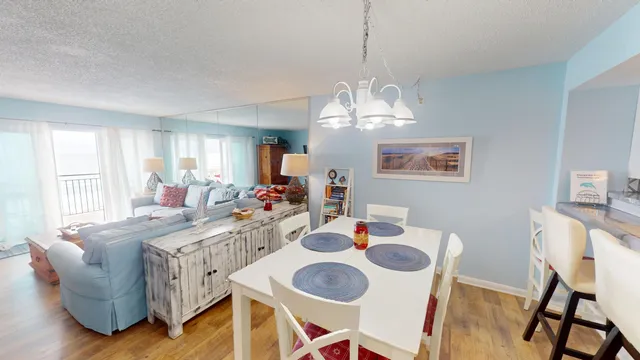 a view of a dining room with furniture a chandelier and wooden floor