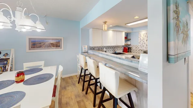 a kitchen with stainless steel appliances kitchen island a table chairs in it and wooden floors