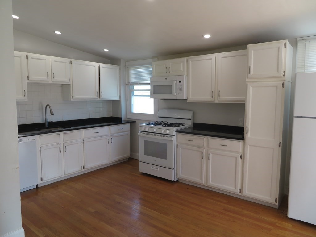 35 Madison Street Malden, MA 02148 - Photo 3 of 16 a kitchen with granite countertop white cabinets and white appliances