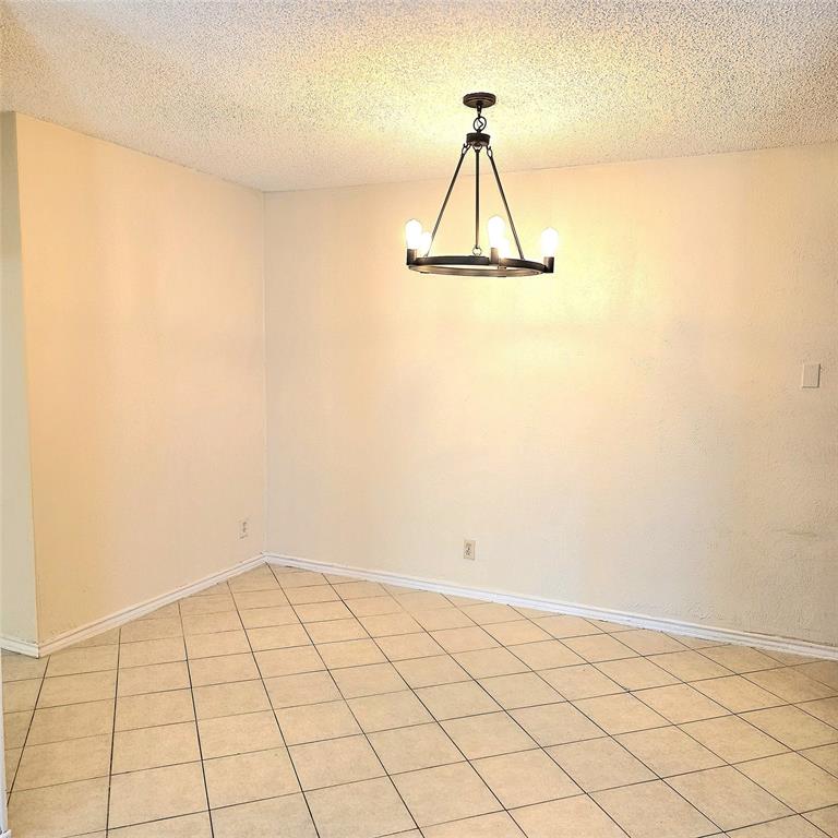 407 Gatewood Road, Unit 407 Garland, TX 75043 - Photo 3 of 7 Dining Room with updated chandelier is open to galley kitchen and Living Area for functional living!
