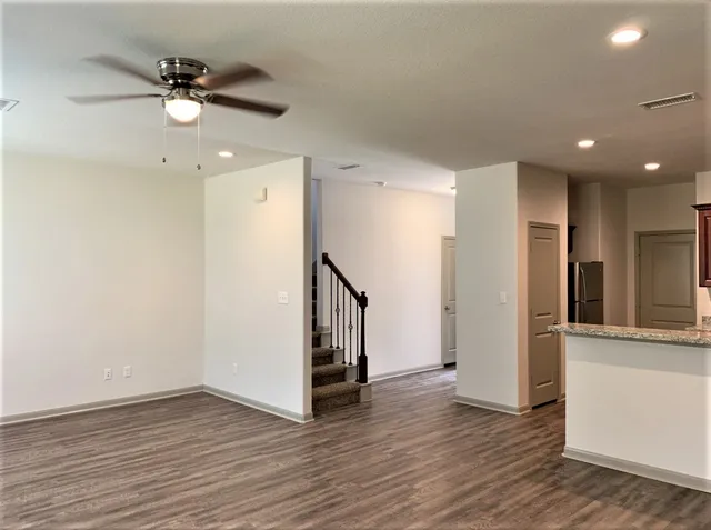 an empty room with wooden floor and a ceiling fan