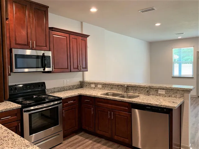 a kitchen with stainless steel appliances granite countertop a stove microwave and sink