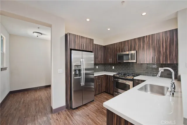 a kitchen with stainless steel appliances granite countertop a refrigerator a sink dishwasher a stove with wooden floors and cabinets