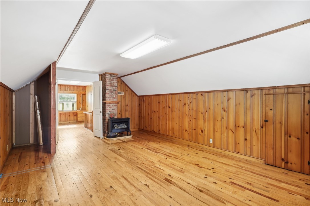 1042 Renfield Road Cleveland Heights, OH 44121 - Photo 28 of 49 Additional living space featuring wooden walls, light hardwood / wood-style floors, vaulted ceiling, and a wood stove