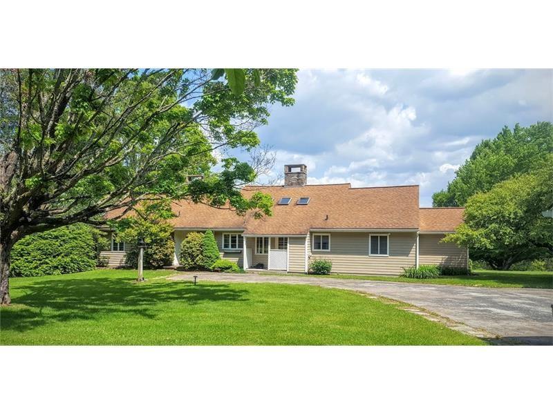 This lovely home is deceiving from the outside, as it opens to beautiful spaces, high ceilings, a soaring stone hearth, guest wing, and walls of windows looking out over the fields and woods beyond.