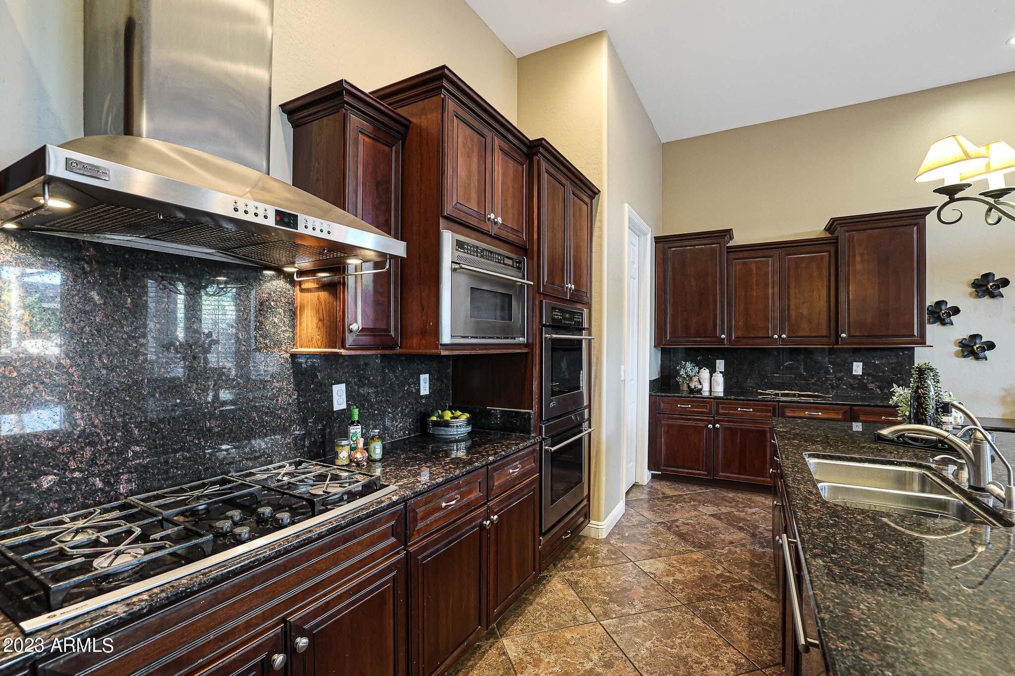 4935 West Yearling Road Phoenix, AZ 85083 - Photo 22 of 57 a kitchen with wooden cabinets and a stove top oven