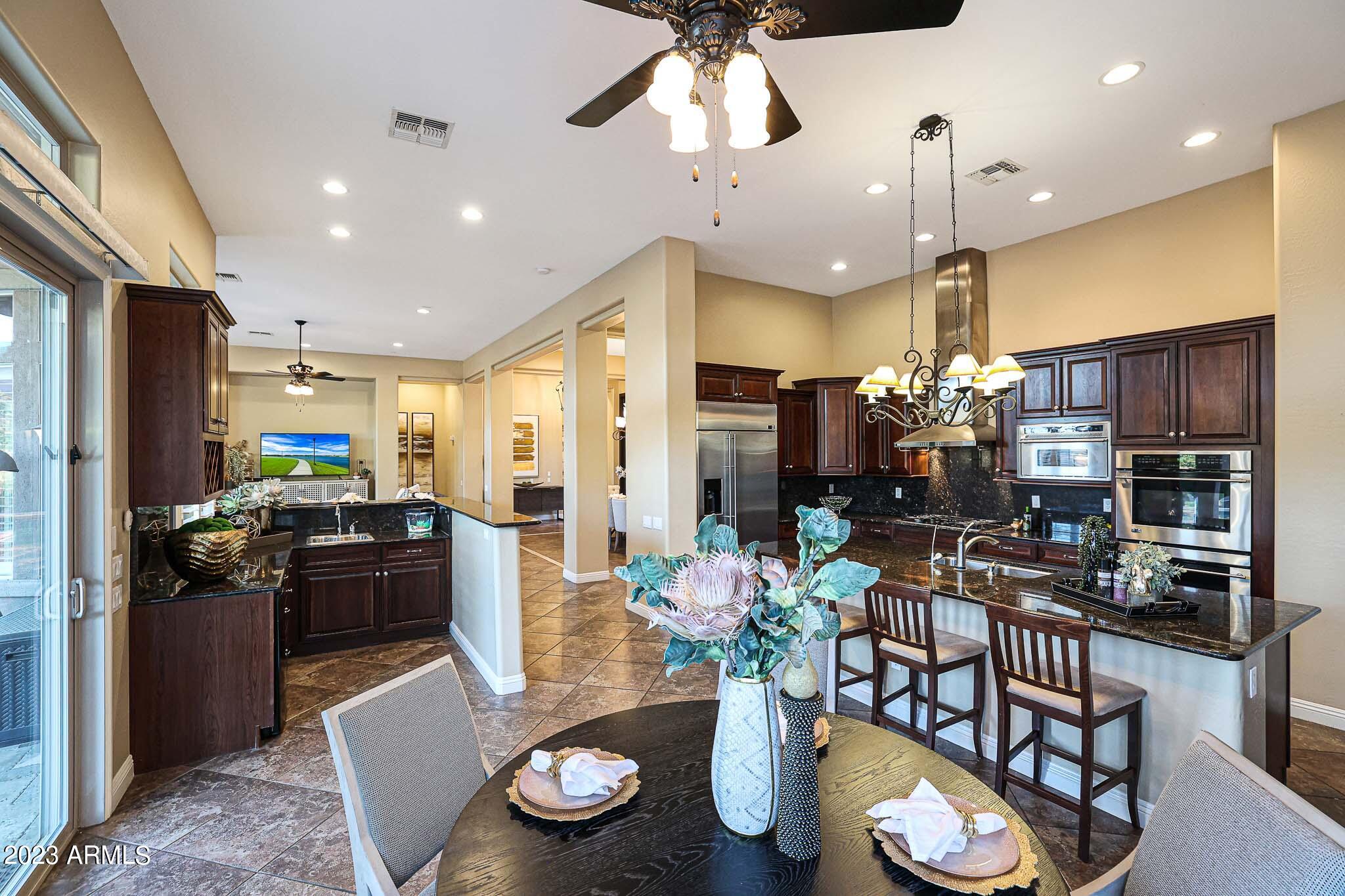 4935 West Yearling Road Phoenix, AZ 85083 - Photo 5 of 57 a kitchen with stainless steel appliances kitchen island granite countertop a refrigerator a stove a microwave oven a dining table and chairs with wooden floor