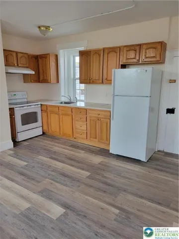 a kitchen with granite countertop a refrigerator and a stove top oven