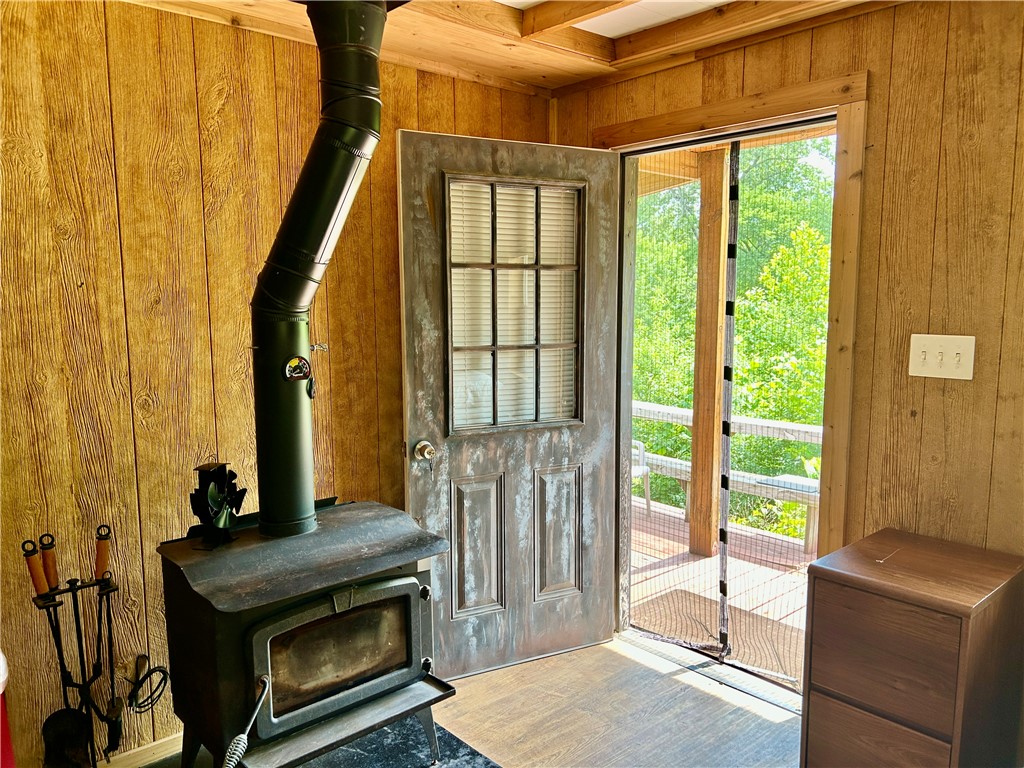462789 East 820 Road Stilwell, OK 74960 - Photo 12 of 48 Wood-paneled interior walls, wood-finish flooring, and a wood-burning stove with a metal flue