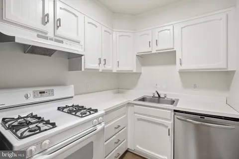a kitchen with white cabinets and appliances
