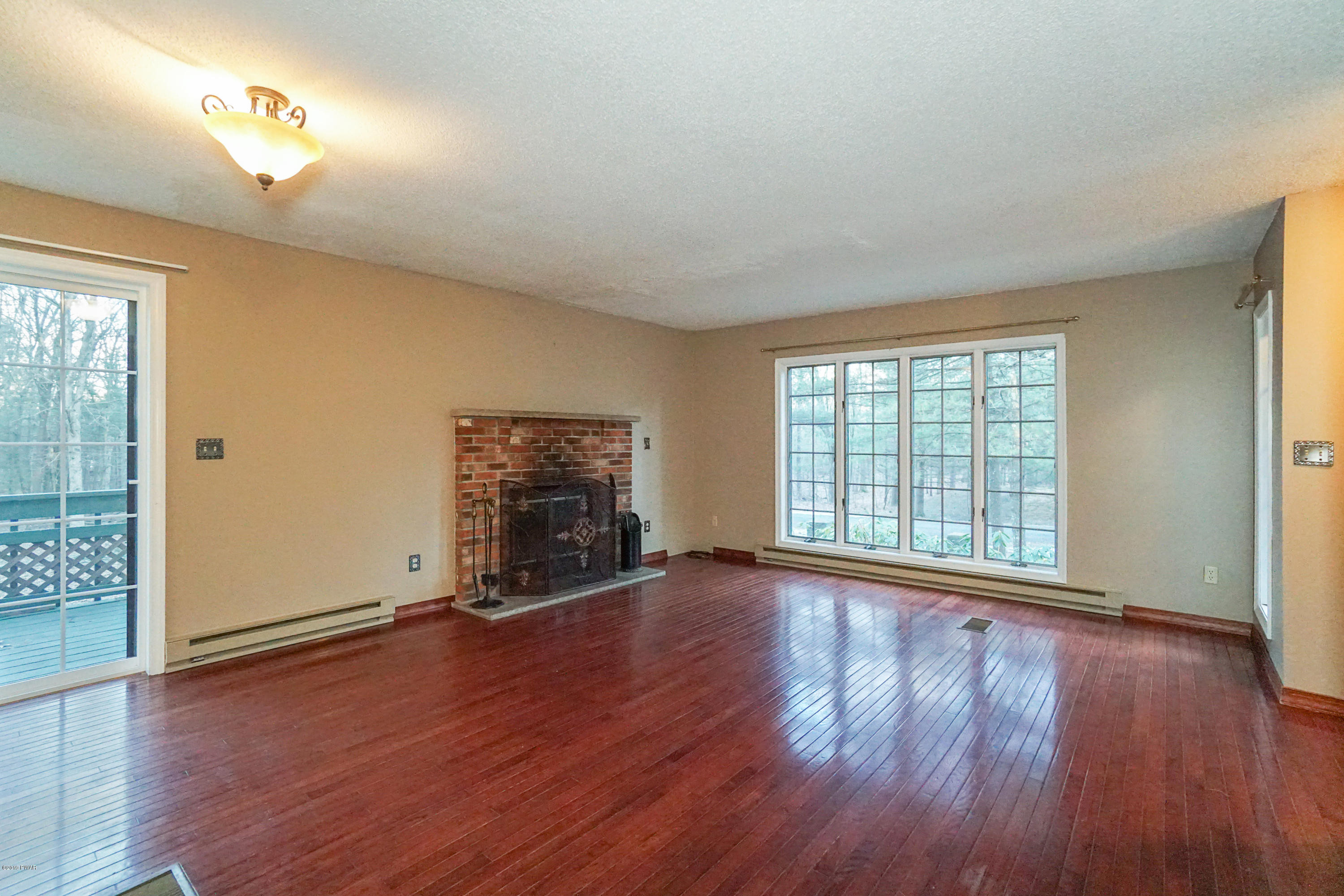 145 Hound Road Dingmans Ferry, PA 18328 - Photo 7 of 20 an empty room with wooden floor and windows