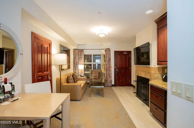 a living room with furniture a flat screen tv and a refrigerator