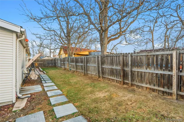 a view of backyard with wooden fence and a large tree