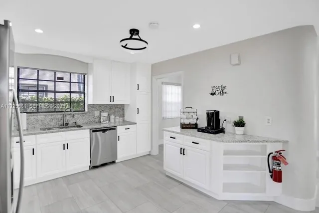 a kitchen with granite countertop a sink stainless steel appliances and cabinets