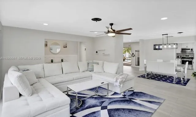 a living room with furniture a white walls and a ceiling fan