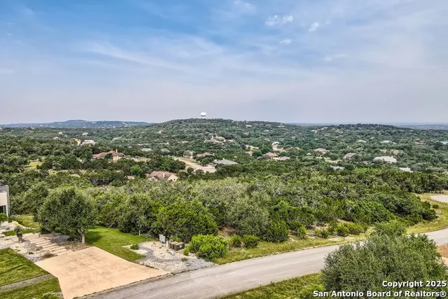 an aerial view of residential houses with outdoor space and trees