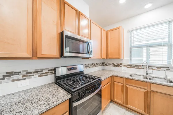 a kitchen with stainless steel appliances granite countertop a stove a sink and a microwave
