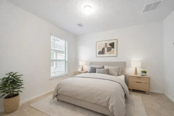 a bedroom with a large bed and a potted plant