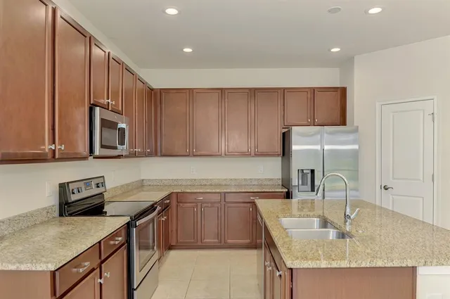 a kitchen with kitchen island granite countertop a sink a stove and refrigerator
