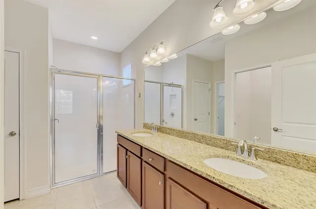 a bathroom with a granite countertop sink a mirror and a shower