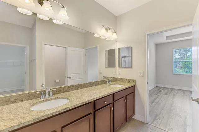 a bathroom with a granite countertop double vanity sink and a mirror