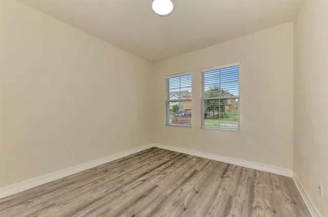 an empty room with wooden floor and windows