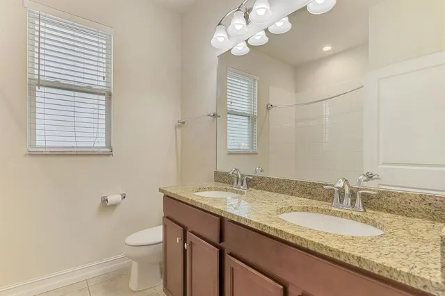 a bathroom with a granite countertop sink a toilet and mirror