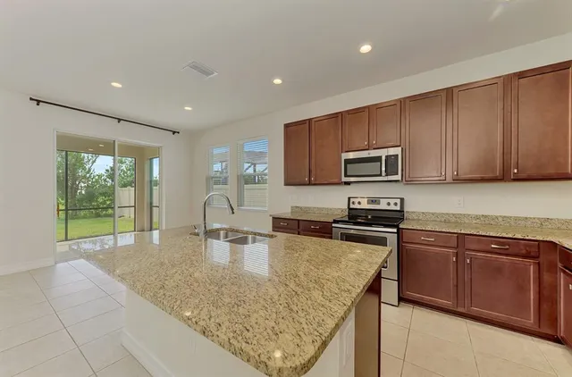 a kitchen with kitchen island granite countertop a sink stove top oven and microwave