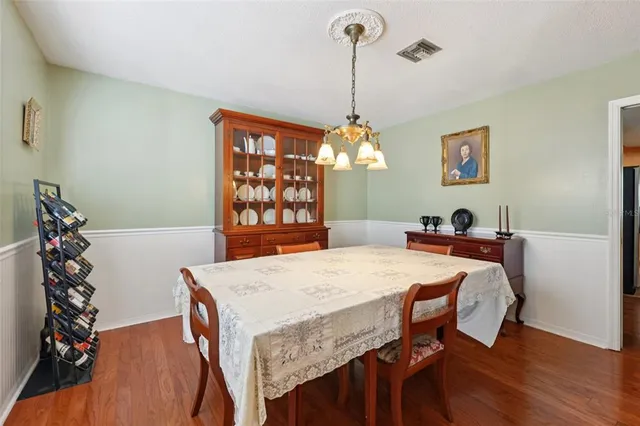 a dining room with wooden floor a chandelier a wooden table and chairs