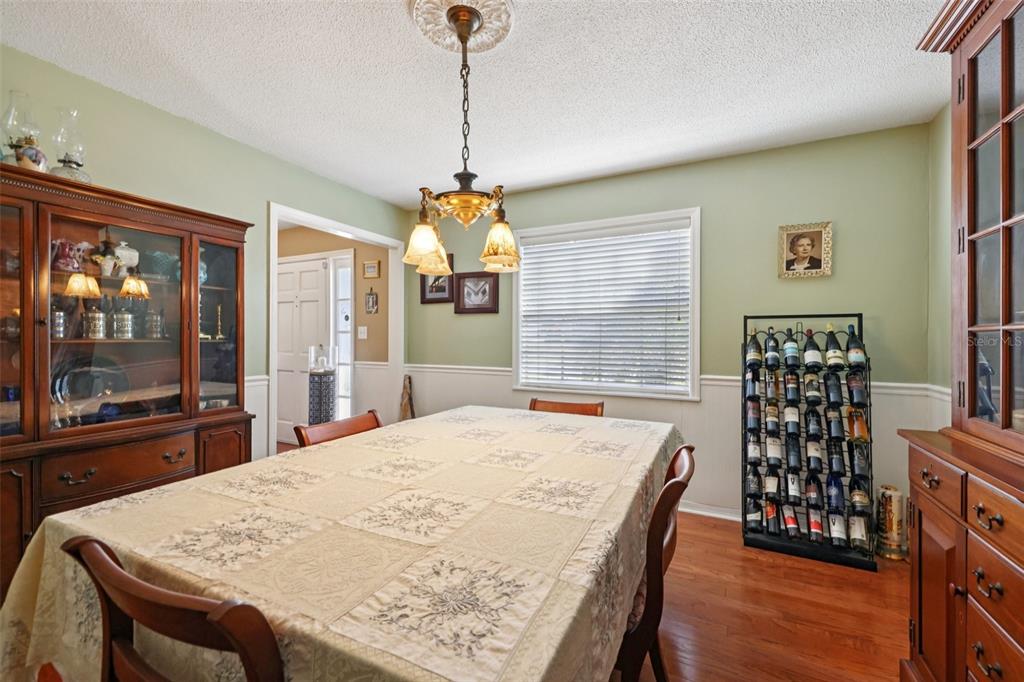 1105 South 9th Street Leesburg, FL 34748 - Photo 16 of 69 a dining room with wooden floor a chandelier a wooden table and chairs