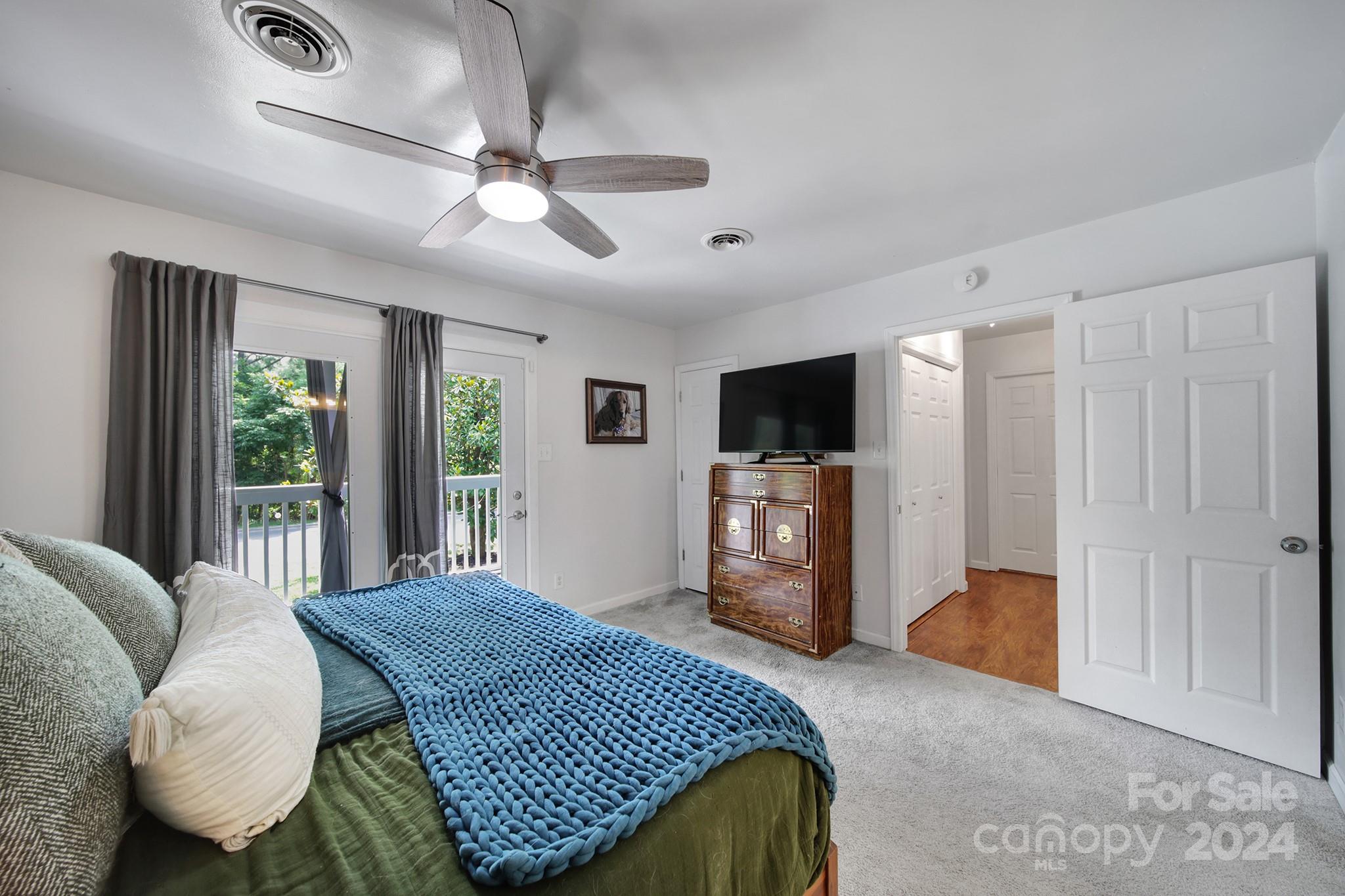 6027 Windjammer Drive Tega Cay, SC 29708 - Photo 18 of 27 a spacious bedroom with a balcony a bed and a television