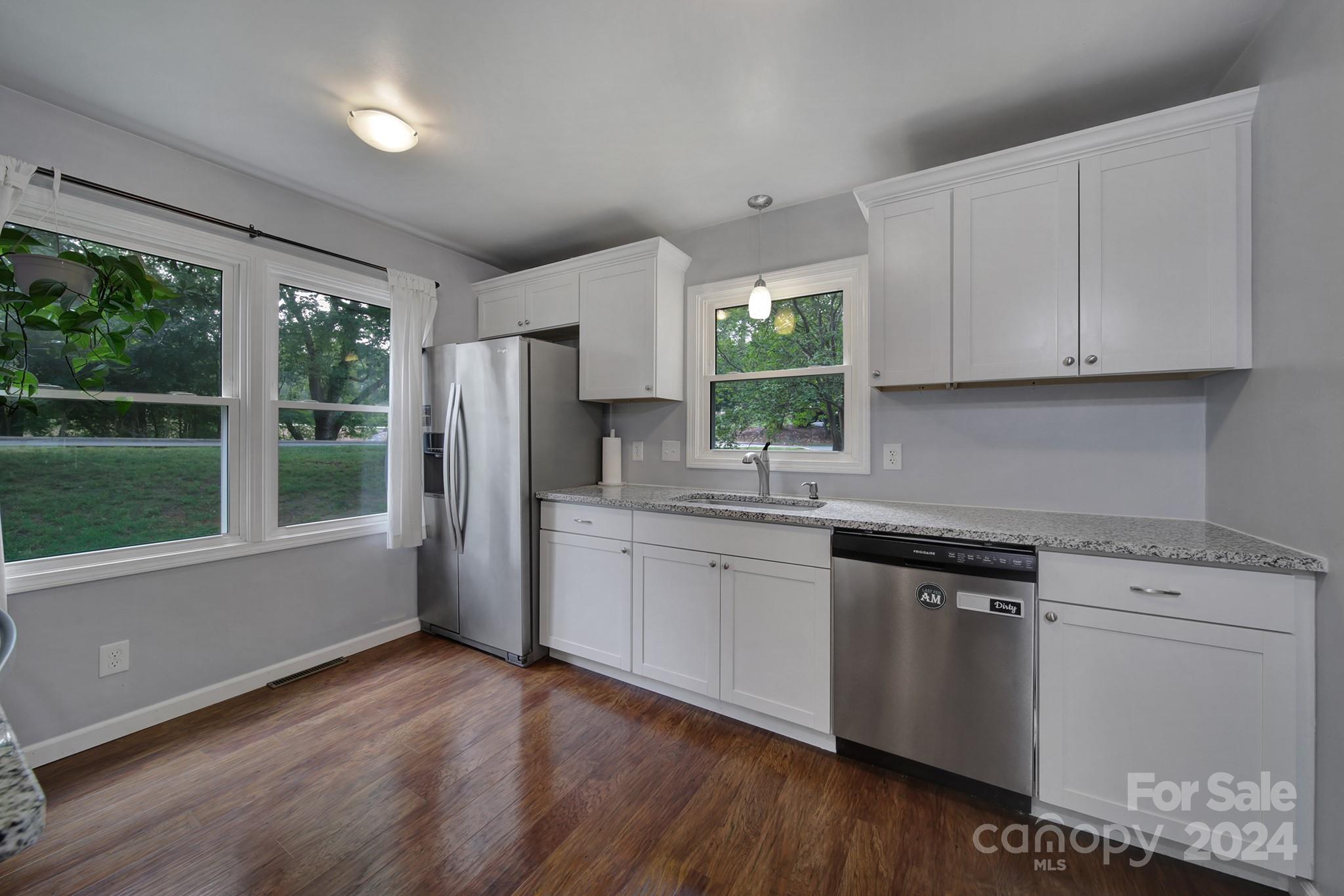 6027 Windjammer Drive Tega Cay, SC 29708 - Photo 10 of 27 a kitchen with granite countertop white cabinets and wooden floor
